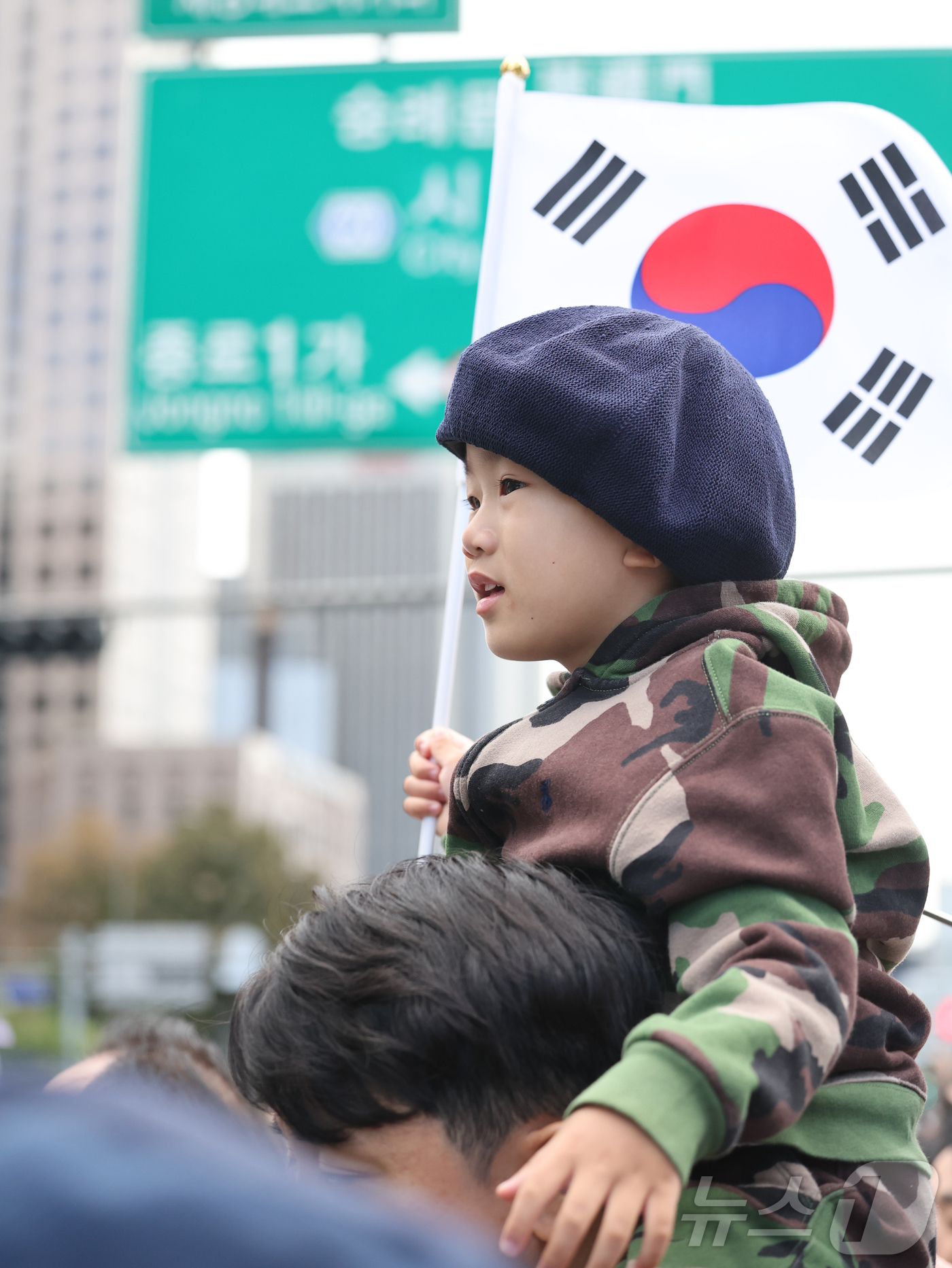 (서울=뉴스1) 황기선 기자 = 국군의 날인 1일 서울 종로구 광화문광장 일대에서 한 어린이가 태극기를 들고 ‘건군 76주년 국군의날 시가행진’을 보기 위해 목마를 탄채 기다리고 …