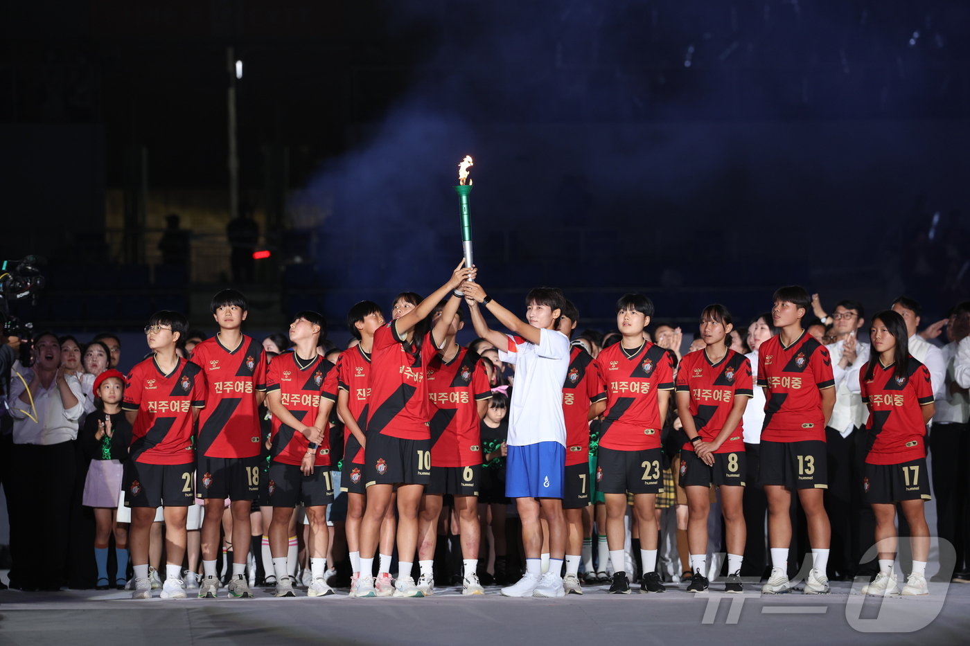 제105회 전국체전 개회식의 성화봉송 최종 주자인 여민지 선수와 진주여중 축구부 선수들이 성화를 들어보이고 있다.&#40;경남도 제공&#41;