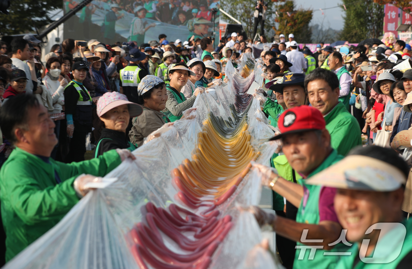 (이천=뉴스1) 김영운 기자 = ‘제23회 이천쌀문화축제’가 개막한 16일 오후 경기 이천시 모가면 이천농업테마공원에서 행사 관계자들이 600m 가래떡을 만들고 기념촬영을 하고 있 …