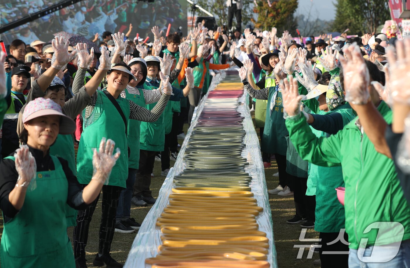 본문 이미지 - ‘제23회 이천쌀문화축제’가 개막한 16일 오후 경기 이천시 모가면 이천농업테마공원에서 행사 관계자들이 600m 가래떡을 만들고 기념촬영을 하고 있다. 2024.10.16/뉴스1 ⓒ News1 김영운 기자