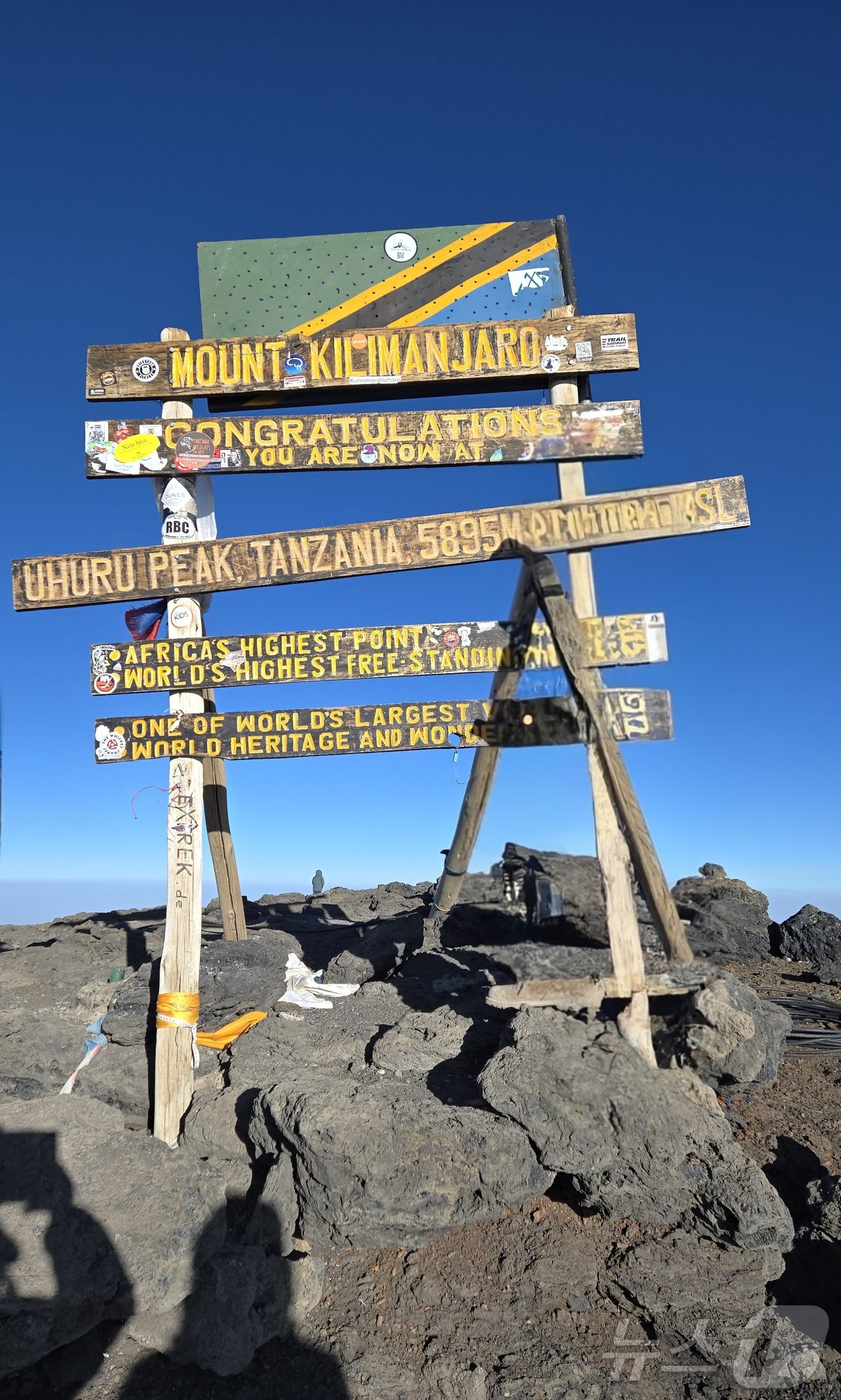 우후루 피크&#40;5895m&#41; 정상의 표지판. 맨 위의 탄자니아 국기 아래 산 이름과 환영인사, 높이 등이 나무판자에 쓰여 걸려 있다.2024.10.4./뉴스1 ⓒ News1 조영석 기자