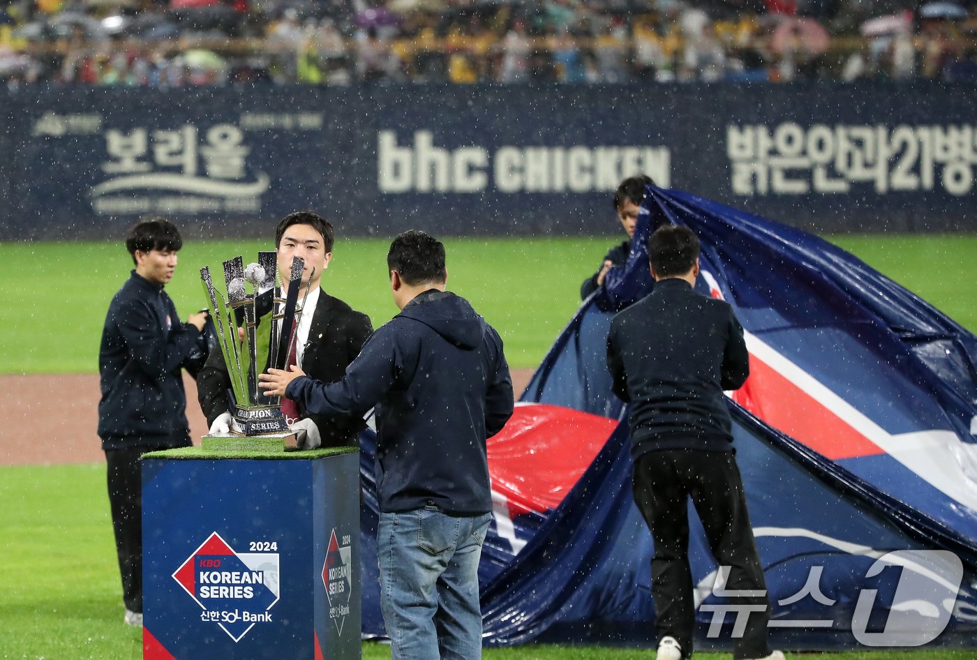 본문 이미지 - 21일 오후 광주 기아챔피언스필드에서 열린 프로야구 '2024 신한 SOL 뱅크 KBO 포스트시즌' 한국시리즈 1차전 삼성 라이온즈와 KIA 타이거즈의 경기가 우천으로 지연되자 관계자들이 개막 행사를 위해 준비된 우승 트로피를 급히 정리하고 있다. 2024.10.21/뉴스1 ⓒ News1 오대일 기자