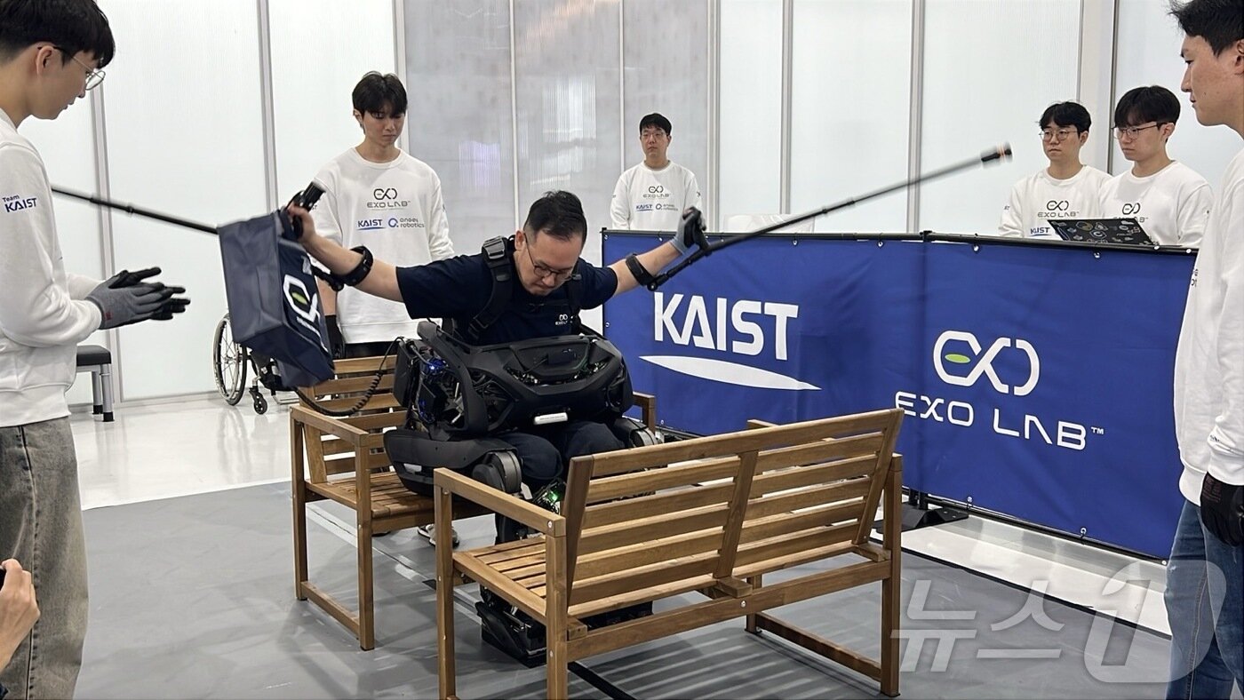 본문 이미지 - 김승환 선수가 24일 대전 대덕구에서 열린 '차세대 웨어러블 로봇 공개 기자 간담회'에서 좁은 의자 사이를 통과해 앉은 뒤 지팡이를 들어 보이고 있다. 2024.10.24/뉴스1 ⓒ 뉴스1 김민재 기자