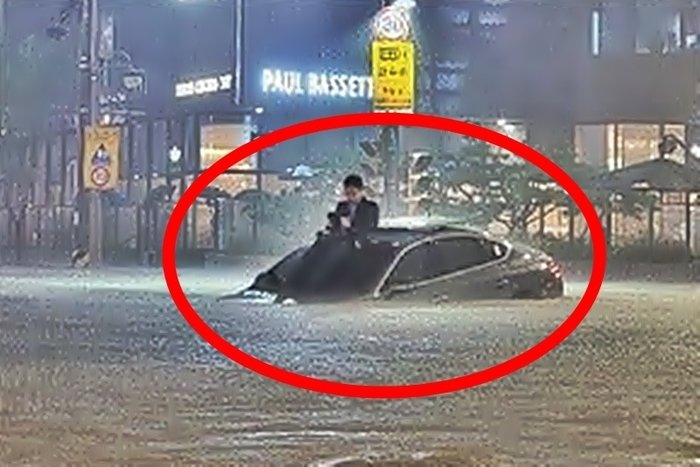 본문 이미지 - 지난 2022년 8월 10일, 서울 강남에 내린 폭우로 도로가 침수되자 제네시스 차 지붕 위로 올라가 구조를 기다린 남성. (온라인 커뮤니티)