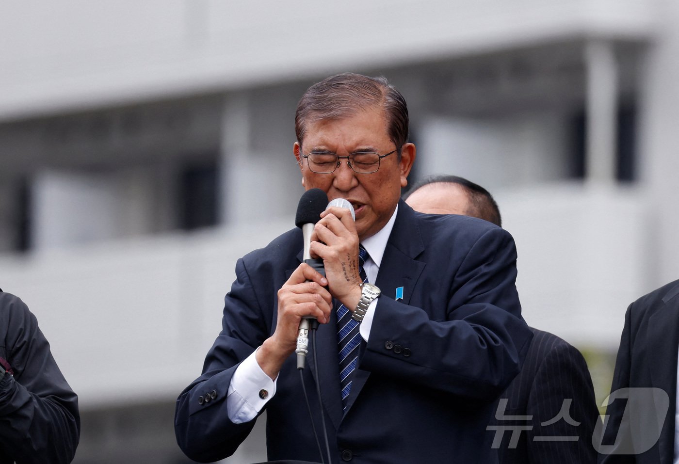 본문 이미지 - 26일 일본 도쿄에서 자민당을 이끄는 이시바 시게루 총리가 마이크에 두 손을 모으고 간절한 표정으로 길거리 연설을 하고 있다. 2024.10.26/ ⓒ 로이터=뉴스1 ⓒ News1 권진영 기자