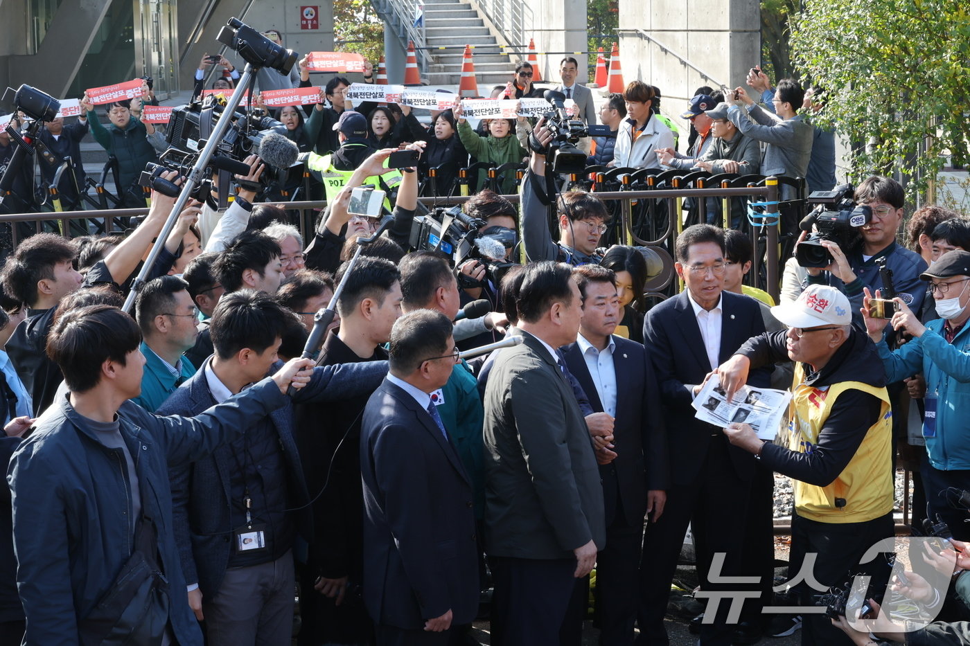 최성룡 납북자피해가족연합회 대표가 31일 오전 경기도 파주시 임진각 내 6·25전쟁납북자기념관 앞에서 대북 전단 살포를 시도하던 중 김경일 파주시장을 비롯한 민주당 의원들과 대화하고 있다. 뒤로는 평화위기파주비상행동 등 시민단체가 대북전단 살포를 규탄하는 손팻말을 들고 있다. 2024.10.31/뉴스1 ⓒ News1 이재명 기자