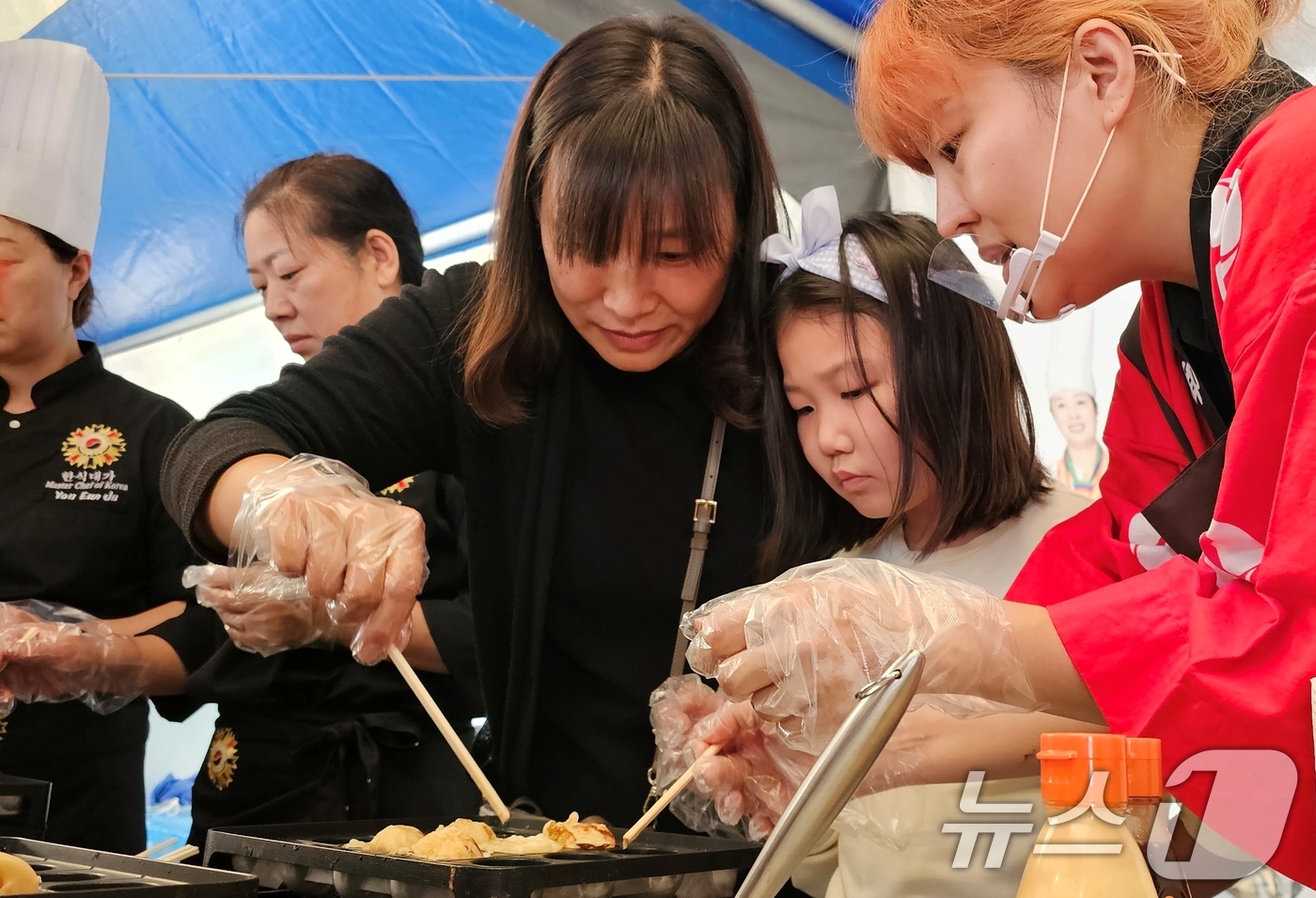 (구미=뉴스1) 정우용 기자 = 5일 구미시청앞 복개천 송정맛길에서 열린 구미푸드페스티벌 한일음식 교류전 코너에서 일본요리사가 일본음식 체험을 하는 어린이에게 요리하는 방법을 알려 …