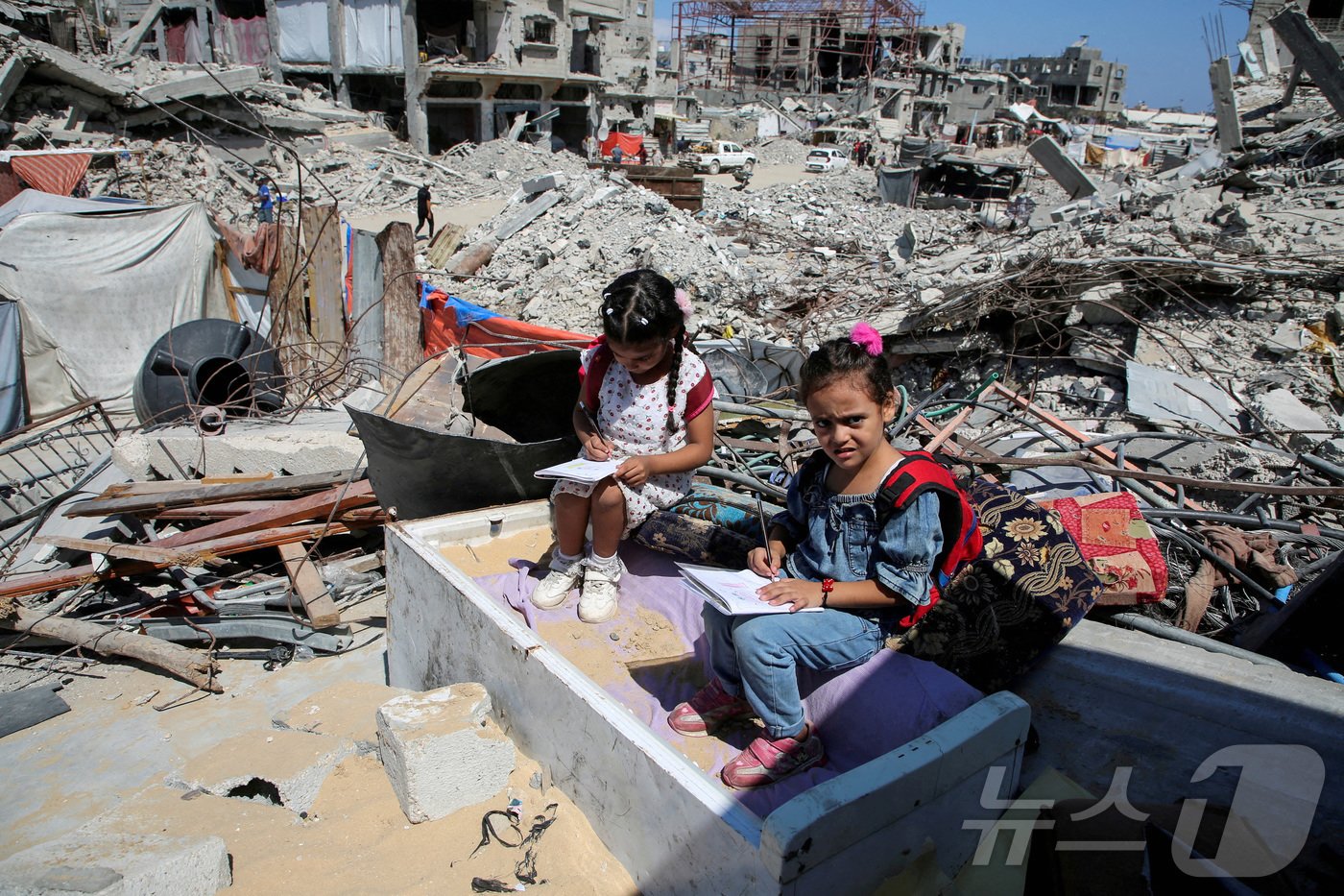 본문 이미지 - 지난 9월 4일(현지시간) 팔레스타인 가자지구 남부의 칸유니스에서 팔레스타인 학생들이 전쟁으로 폐허가 된 교사 이스라 아부 무스타파의 집 잔해 위에 쪼그려 앉아 공부하고 있다. 2024.09.04 ⓒ 로이터=뉴스1 ⓒ News1 김지완 기자