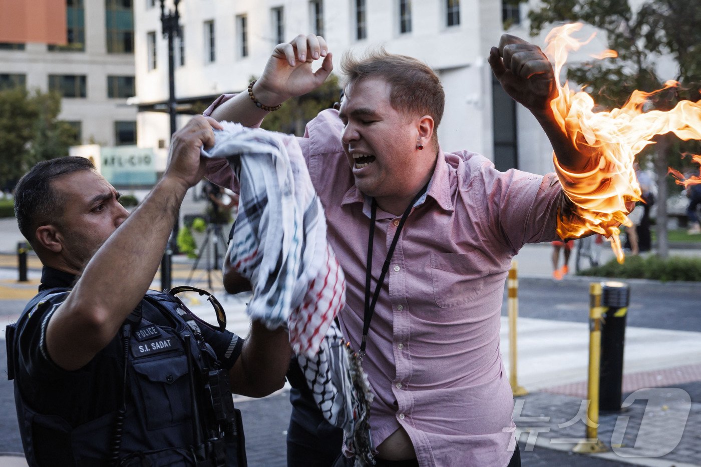 본문 이미지 - 5일(현지시간) 미국 워싱턴 백악관 인근에서 벌어진 반(反) 이스라엘 시위에서 사진기자인 새무엘 메나가 시위 현장에 접근해 자신의 몸에 불을 붙였다. 사진은 경찰이 팔레스타인 전통 스카프인 케이폐를 흔들어 불을 끄는 모습. 2024.10.05 ⓒ AFP=뉴스1 ⓒ News1 최종일 기자