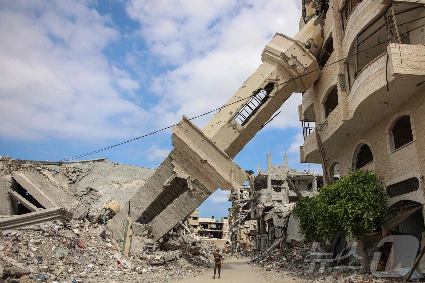 본문 이미지 - 한 팔레스타인 주민이 7일 가자시티 인근 수자이야에서 이스라엘군의 공습에 파괴돼 기울어져 있는 사원 종탑 아래를 지나고 있다. 꼭 1년 전 하마스의 기습으로 시작된 이스라엘과의 가자전쟁은 아직도 계속되고 있다. 2024.10.07 ⓒ AFP=뉴스1 ⓒ News1 정지윤 기자