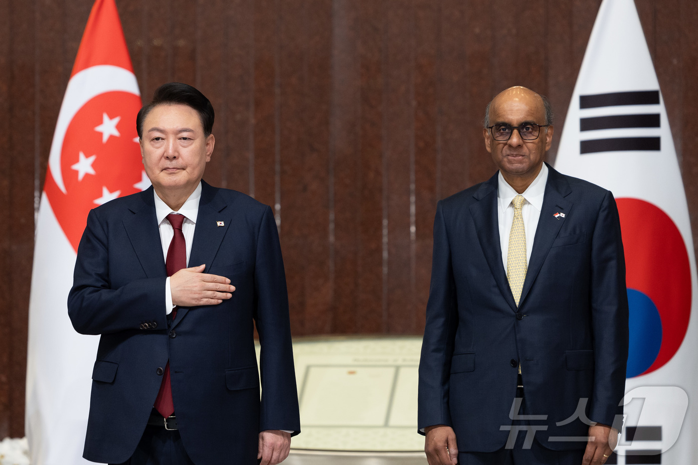 (서울=뉴스1) 박지혜 기자 = 윤석열 대통령이 8일(현지시간) 싱가포르 의회에서 열린 공식환영식에서 애국가가 연주되자 국기에 경례하고 있다.  오른쪽은 타르만 샨무가라트남 싱가포 …