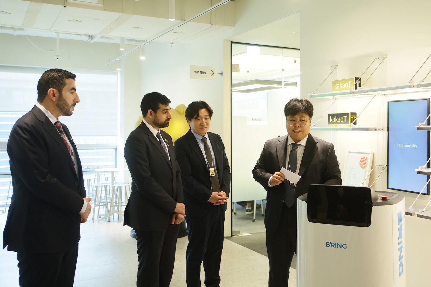 본문 이미지 - 샤르쟈의 셰이크 사우드 왕자를 포함한 샤르자 디지털청 방문단이 카카오모빌리티의 로봇 서비스 브링을 체험하고 있다.(카카오모빌리티 제공)