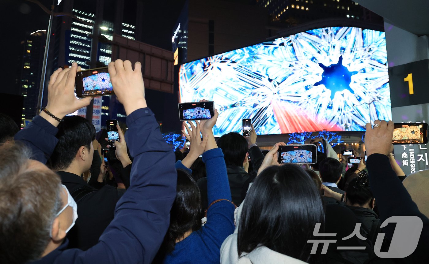 본문 이미지 - 1일 오후 서울 중구 신세계백화점 본점 앞을 찾은 시민들이 외벽에 설치된 LED 사이니지 '신세계스퀘어'에서 펼쳐진 미디어 파사드를 휴대전화로 촬영하고 있다. 2024.11.1/뉴스1 ⓒ News1 박정호 기자