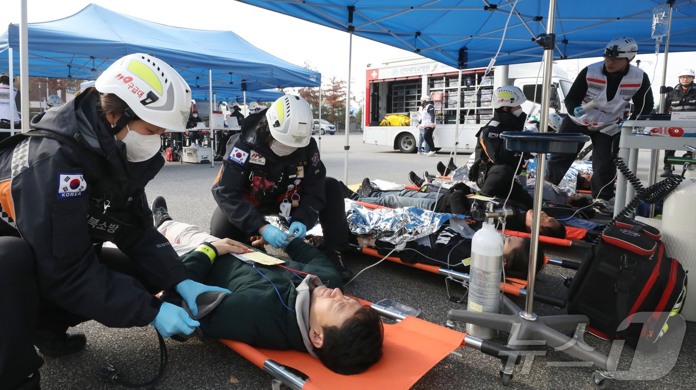 본문 이미지 - 20일 전주시 덕진구 팔복LH아파트 및 더 메이호텔에서 행정안전부를 비롯한 전북소방본부, LH 등이 참여한 가운데 열린 유관기관합동 전기차 화재 대응 제4차 READY Korea 훈련에서 현장응급의료소 의료진이 부상자를 치료하고 있다. 2024.11.