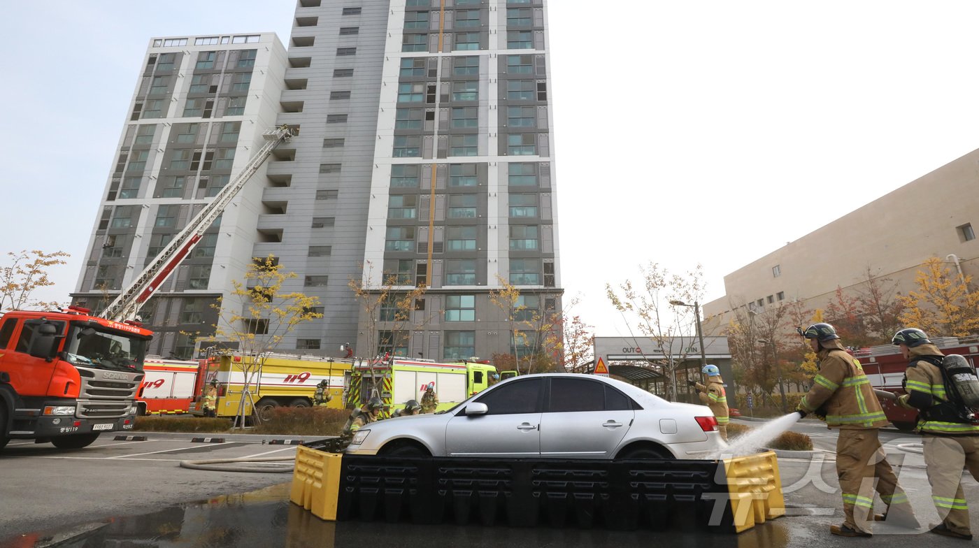 본문 이미지 - 20일 전주시 덕진구 팔복LH아파트 및 더 메이호텔에서 행정안전부를 비롯한 전북소방본부, LH 등이 참여한 가운데 열린 유관기관합동 전기차 화재 대응 제4차 READY Korea 훈련에서 소방대원들이 화재 진압한 전기차를 이동식 소화수조로 이동한 뒤 물을 채우고 있다. 2024.11.20/뉴스1 ⓒ News1 김기남 기자