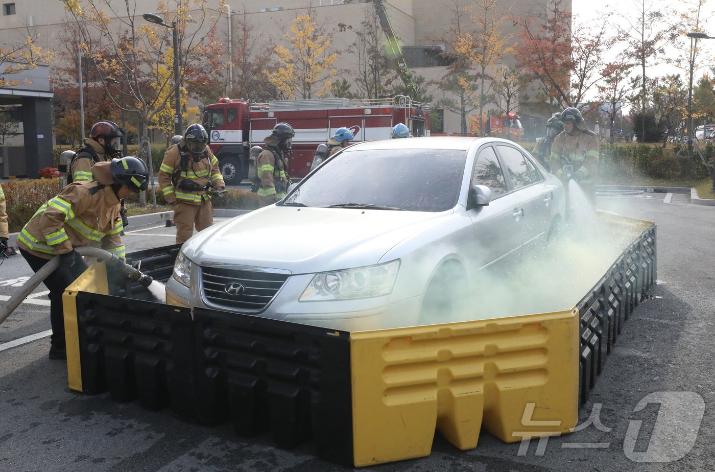 본문 이미지 - 20일 전주시 덕진구 팔복LH아파트 및 더 메이호텔에서 행정안전부를 비롯한 전북소방본부, LH 등이 참여한 가운데 열린 유관기관합동 전기차 화재 대응 제4차 READY Korea 훈련에서 소방대원들이 화재 진압한 전기차를 이동식 소화수조로 이동한 뒤 물을 채우고 있다. 2024.11.20/뉴스1 ⓒ News1 김기남 기자