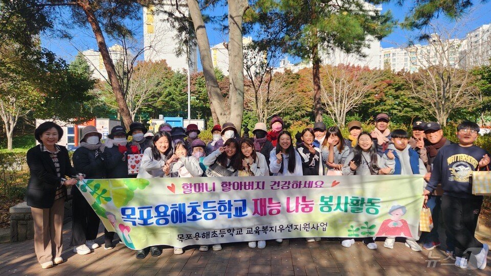 본문 이미지 - 학생들이 학교 주변 환경을 정리 해 주는 어르신들에게 목도리를 전달한 뒤 기념사진을 찍고 있다. (전남교육청 제공)/뉴스1