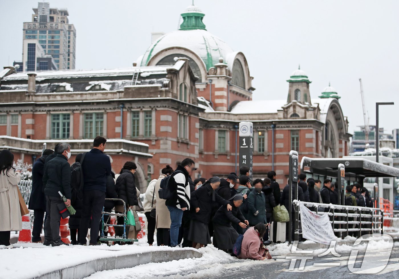 수도권과 강원지역을 중심으로 대설 특보가 발효된 27일 오전 서울 중구 서울역 앞 횡단보도에서 한 여성이 빙판에 미끄러져 넘어지고 있다. 2024.11.27/뉴스1 ⓒ News1 오대일 기자