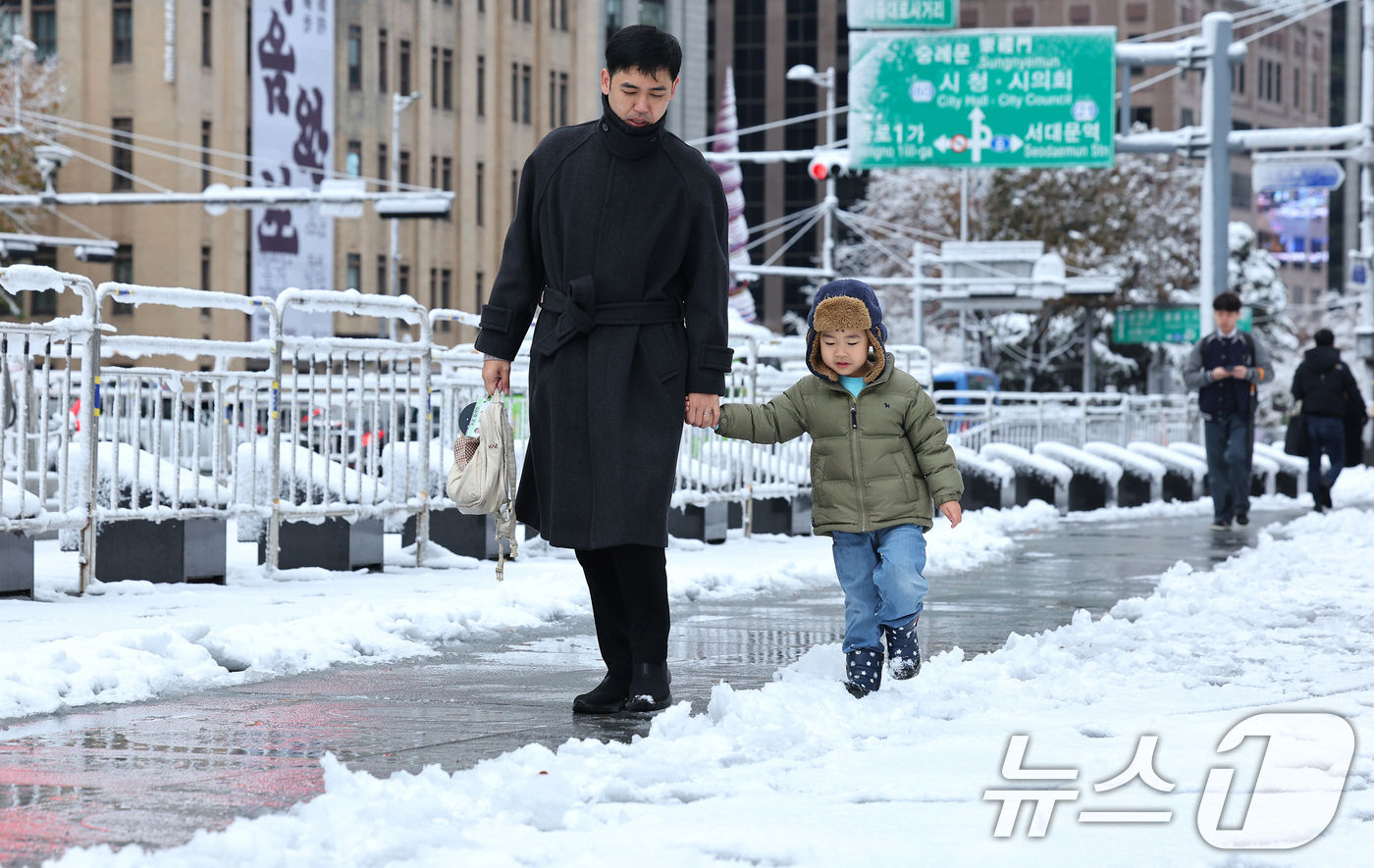 (서울=뉴스1) 장수영 기자 = 많은 눈이 내린 27일 오전 서울 종로구 광화문광장에서 아빠와 아이가 눈 쌓인 길을 걷고 있다. 2024.11.27/뉴스1