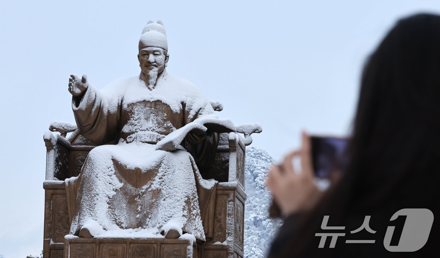 많은 눈이 내린 27일 오전 서울 종로구 광화문광장을 지나는 시민이 눈 쌓인 세종대왕 동상을 촬영하고 있다. 2024.11.27/뉴스1 ⓒ News1 장수영 기자