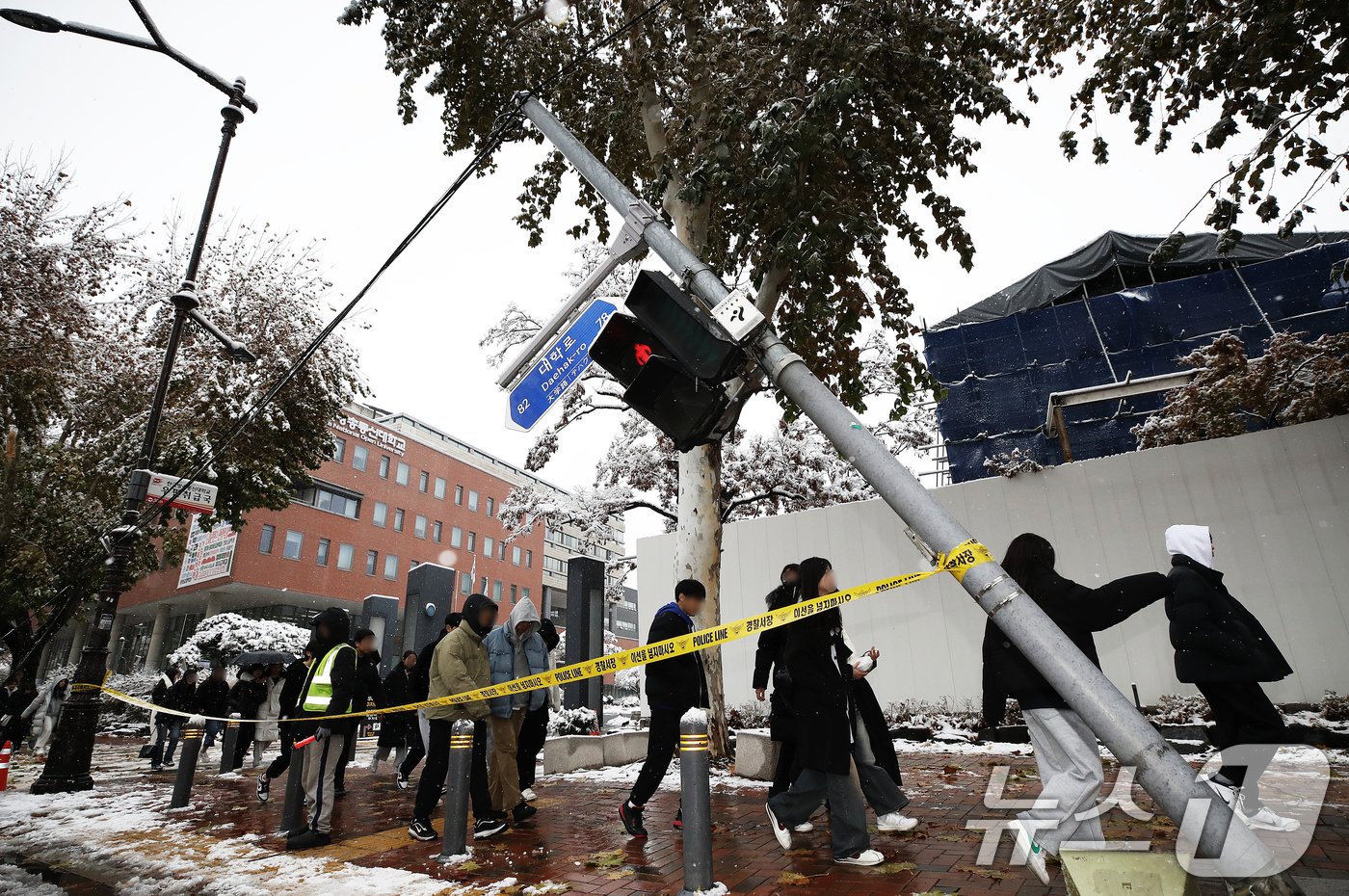 본문 이미지 - 기록적인 첫 눈이 내린 27일 서울 종로구 대학로의 한 횡단보도 신호등이 기울어져 있다. 이 사고는 밤새 내린 폭설의 무게를 견디지 못하고 부러진 가로수가 신호등과 연결된 전선줄을 끌어당겨 발생했으며 인명피해는 없는 것으로 파악됐다. 2024.11.27/뉴스1 ⓒ News1 오대일 기자