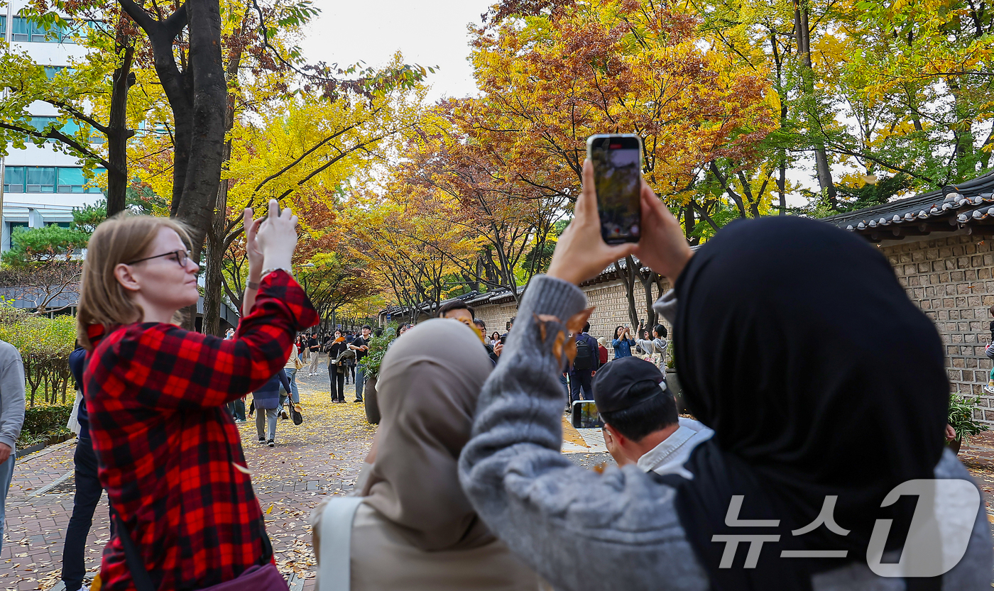 (서울=뉴스1) 김진환 기자 = 서울의 낮 최고기온이 24도 가까이 오르는 등 포근한 날씨를 보인 3일 오후 서울 중구 덕수궁 돌담길에 단풍이 물든 가운데 외국인 관광객들이 늦가을 …