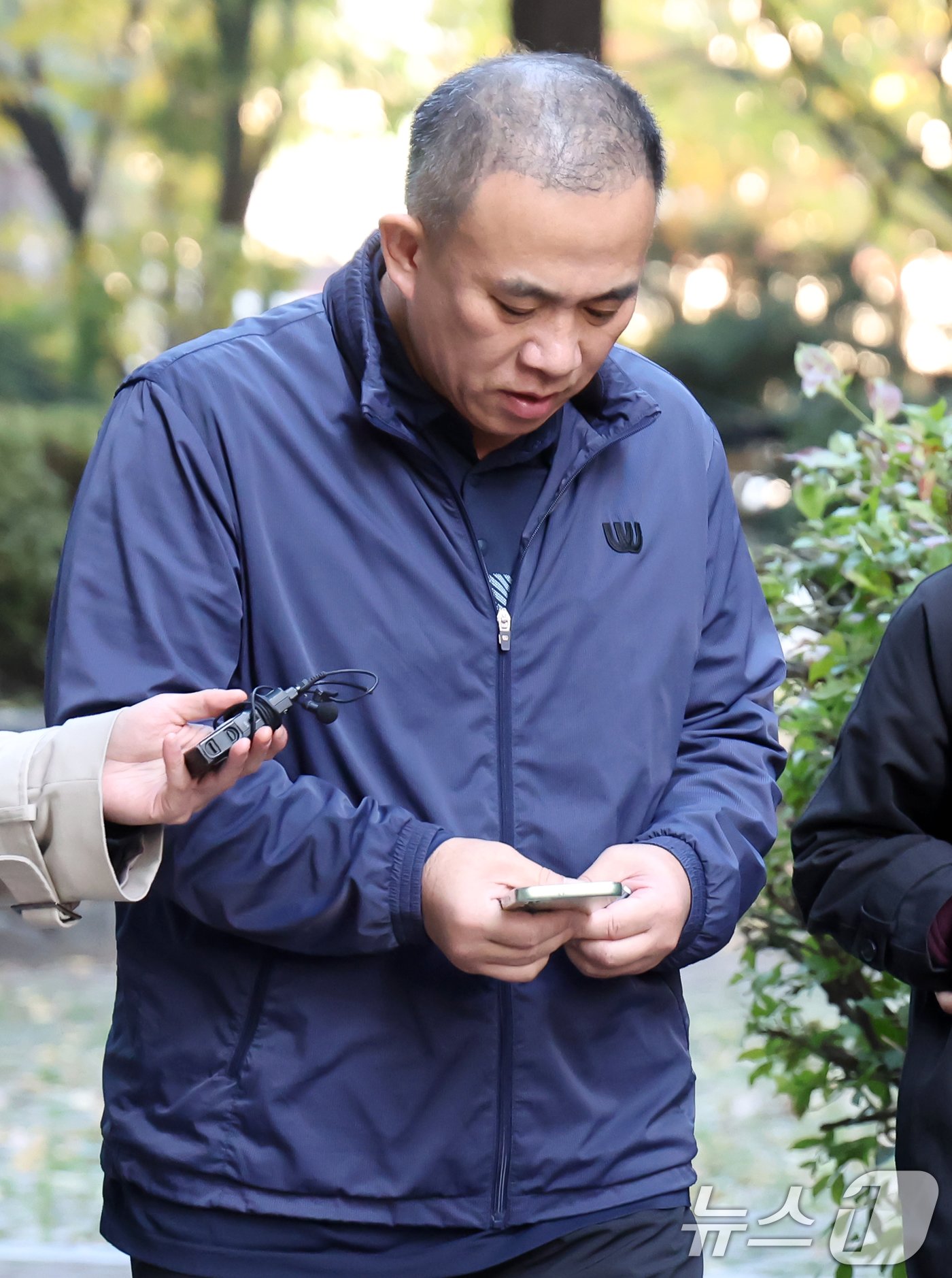 &#39;김건희 여사 공천 개입 의혹&#39;의 핵심 인물인 명태균 씨가 6일 오전 경남 창원의 자택에서 나와 취재진의 질문을 받으며 휴대전화 화면을 바라보고 있다. 2024.11.6/뉴스1 ⓒ News1 민경석 기자