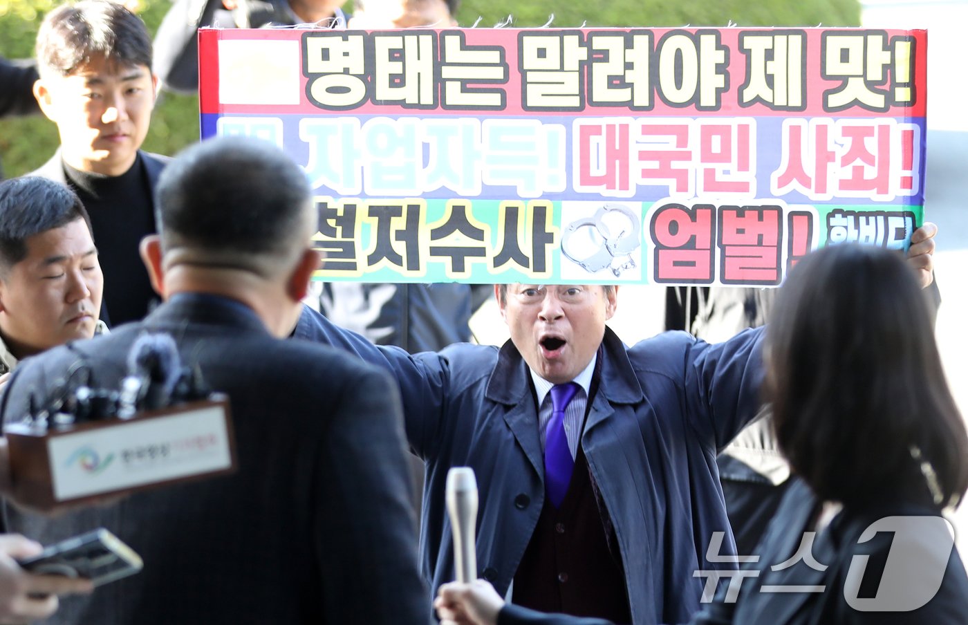 윤석열 대통령 부부 공천 개입 의혹의 핵심 인물인 명태균 씨가 9일 오전 정치자금법 위반 혐의 피의자 신분으로 검찰 조사를 받기 위해 경남 창원시 성산구 창원지방검찰청으로 출석하며 &#39;명태는 말려야 제맛&#39; 등이 적힌 현수막을 든 한 유튜버와 실랑이를 벌이고 있다. 청사로 들어가는 명 씨 뒤에서 한 유튜버가 &#34;어제는 꼬리내리고＂라고 비난하자 명 씨는 뒤돌아서 ＂정신차려＂라고 호통쳤다. 2024.11.9/뉴스1 ⓒ News1 윤일지 기자