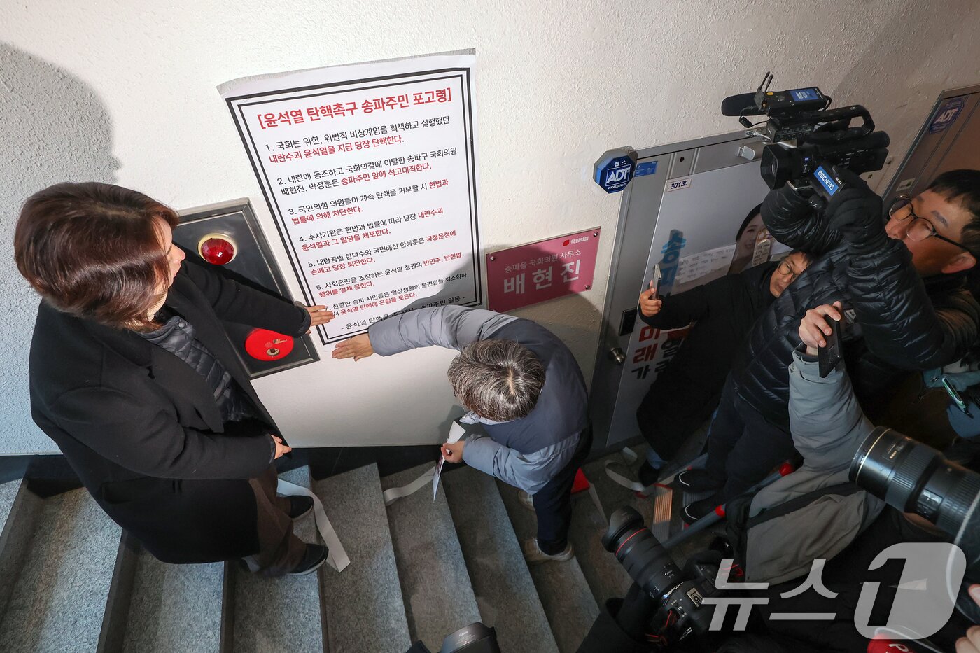 본문 이미지 - 송파연대회의 관계자들이 10일 오전 서울 송파구의 배현진 국민의힘 의원 사무실을 찾아 윤석열 대통령 탄핵 표결에 참여하지 않은 배 의원을 규탄하며 '윤석열 탄핵촉구 송파주민 포고령'을 사무실 출입문 옆 벽면에 부착하고 있다. 2024.12.10/뉴스1 ⓒ News1 민경석 기자