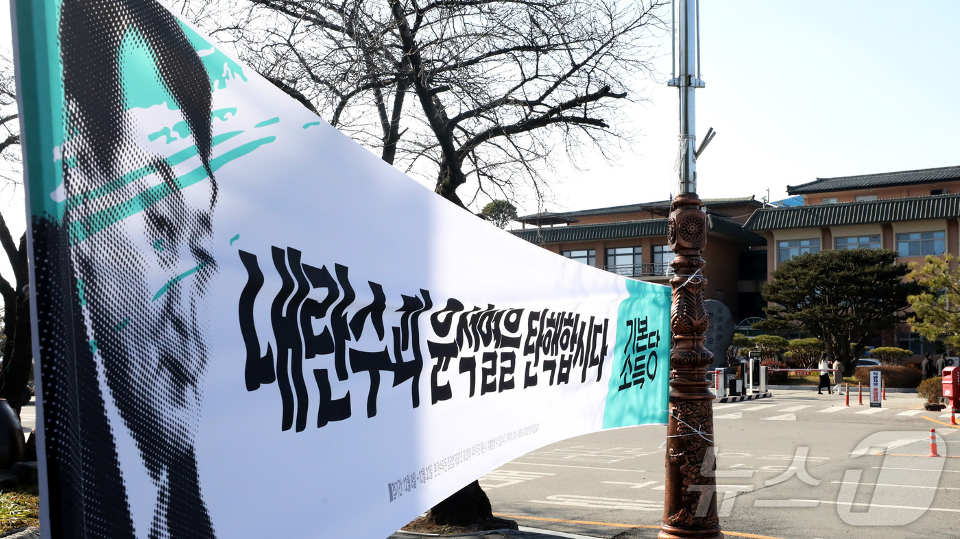 (부여=뉴스1) 김기남 기자 = 10일 오후 충남 부여군청 앞을 지나는 시민들이 윤석열 대통령의 탄핵을 요구하는 플래카드를 지나고 있다.  . 2024.12.10/뉴스1