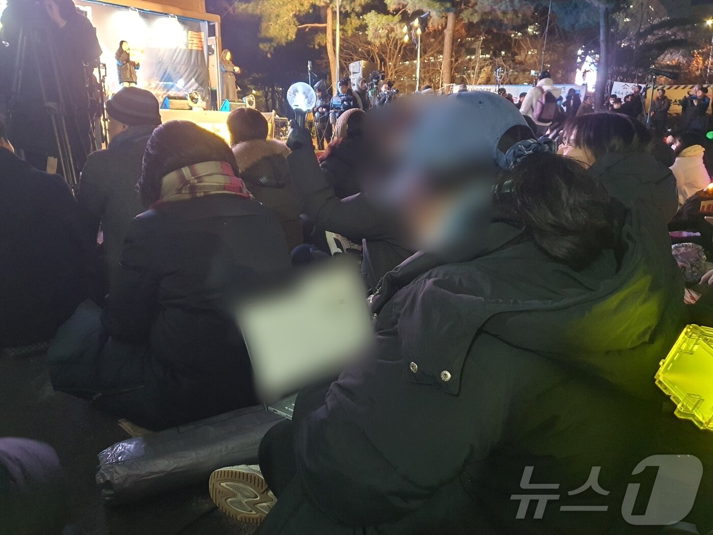 본문 이미지 - 10일 오후 6시 서울 영등포구 국회의사당역 5번 출구 인근에서 열린 대통령 탄핵소추안 통과 촉구 집회에 20대 여성 A 씨가 노트북을 펴고 앉아 있다. 2024.12.10