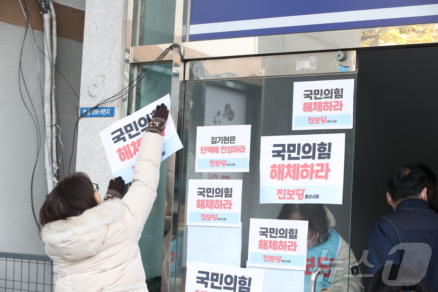 (울산=뉴스1) 김세은 기자 = 진보당 울산시당 관계자 등이 11일 오전 울산 김기현 의원 사무실 건물 창문에 '국민의힘 해체하라' 문구를 붙이고 있다. 2024.12.11/뉴스1 …