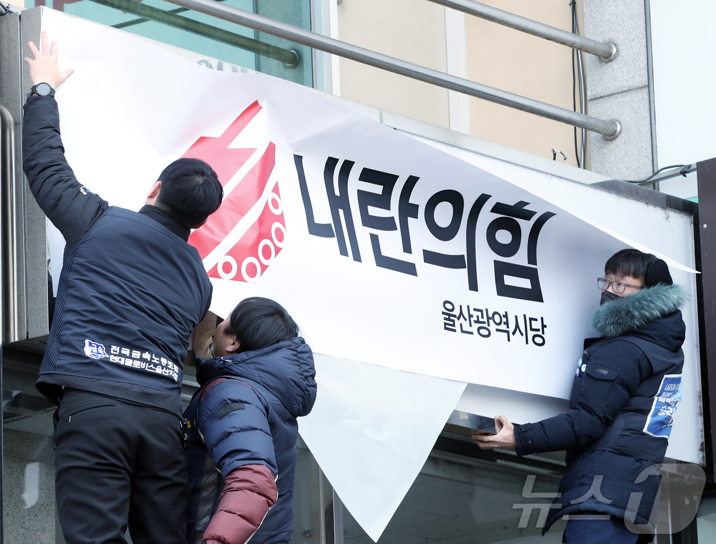 (울산=뉴스1) 김세은 기자 = 윤석열퇴진울산운동본부 관계자들이 11일 오전 국민의힘 울산시당 현판을 '내란의힘'으로 덮고 있다. 2024.12.11/뉴스1