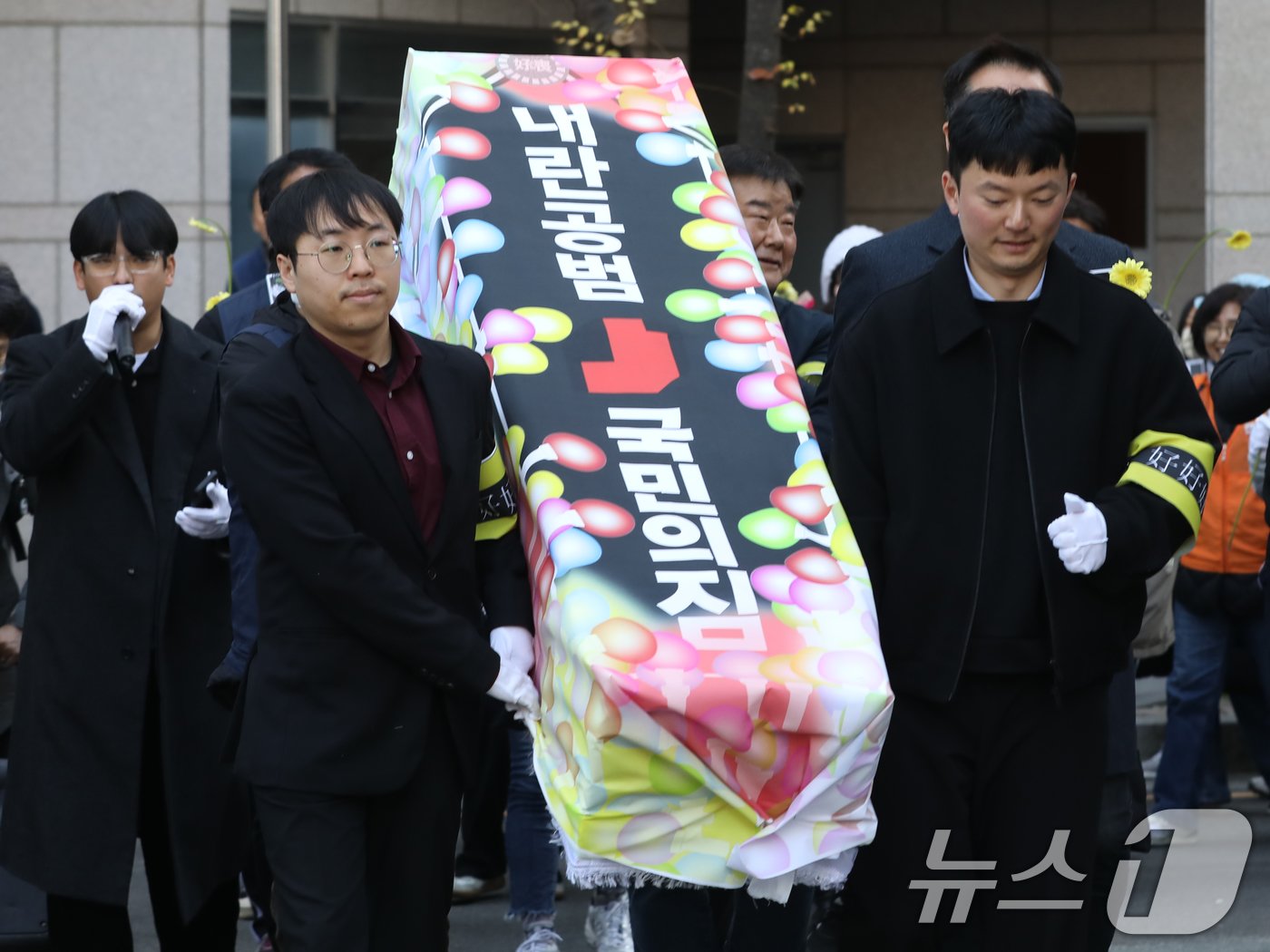 본문 이미지 - 윤석열 정권 퇴진 부산비상행동 구성원들이 11일 오후 부산 수영구 국민의힘 부산시당 앞에서 '내란공범 국민의힘 사망선고 장례식 기자회견'을 마친 뒤 운구 퍼포먼스를 하고 있다. 2024.12.11/뉴스1 ⓒ News1 윤일지 기자