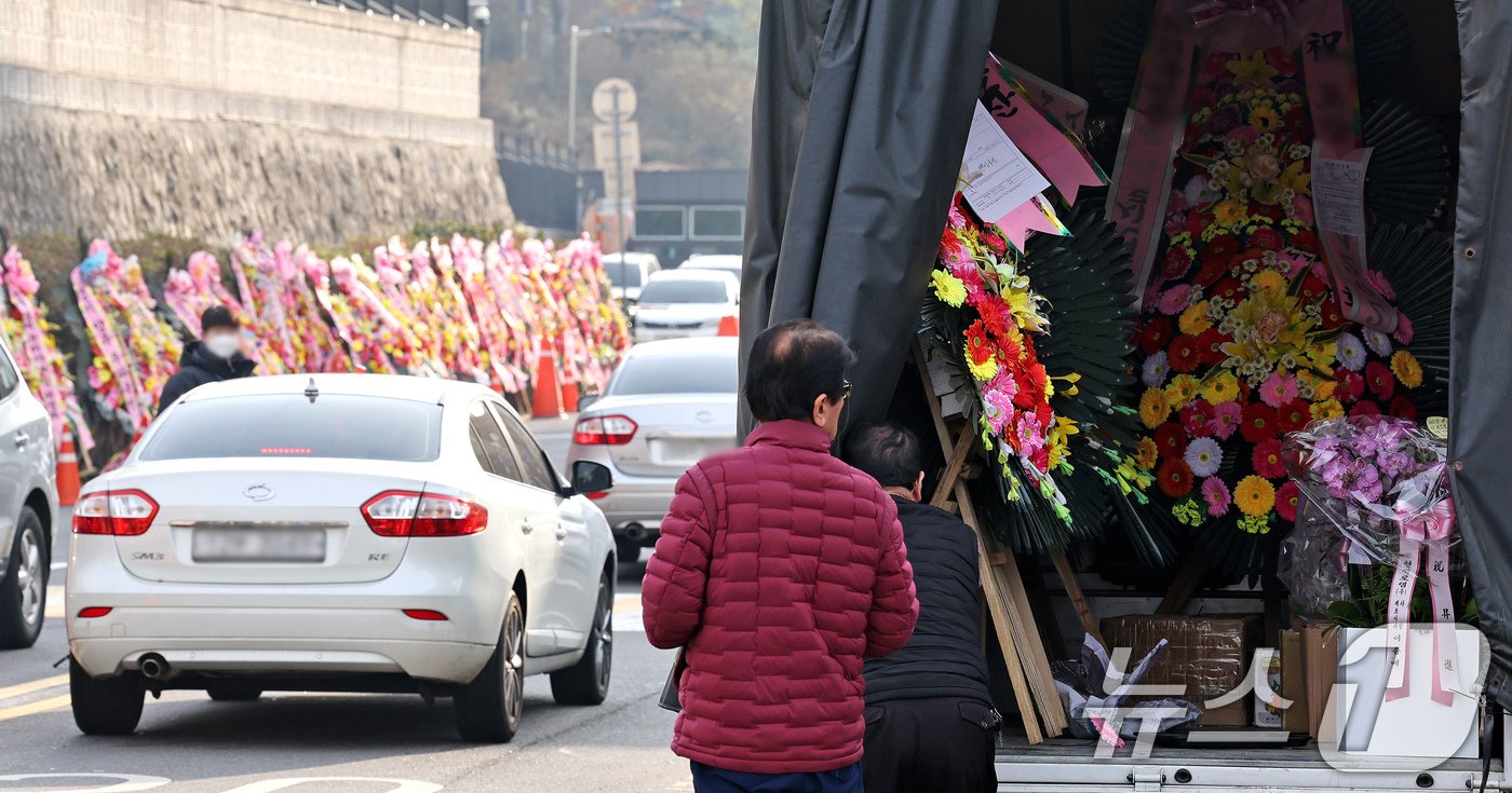 11일 오후 서울 용산구 대통령실 출입문 앞 도로에서 화환 업체 관계자가 윤석열 대통령 지지자들이 보낸 화환을 옮기고 있다. 2024.12.11/뉴스1 ⓒ News1 장수영 기자