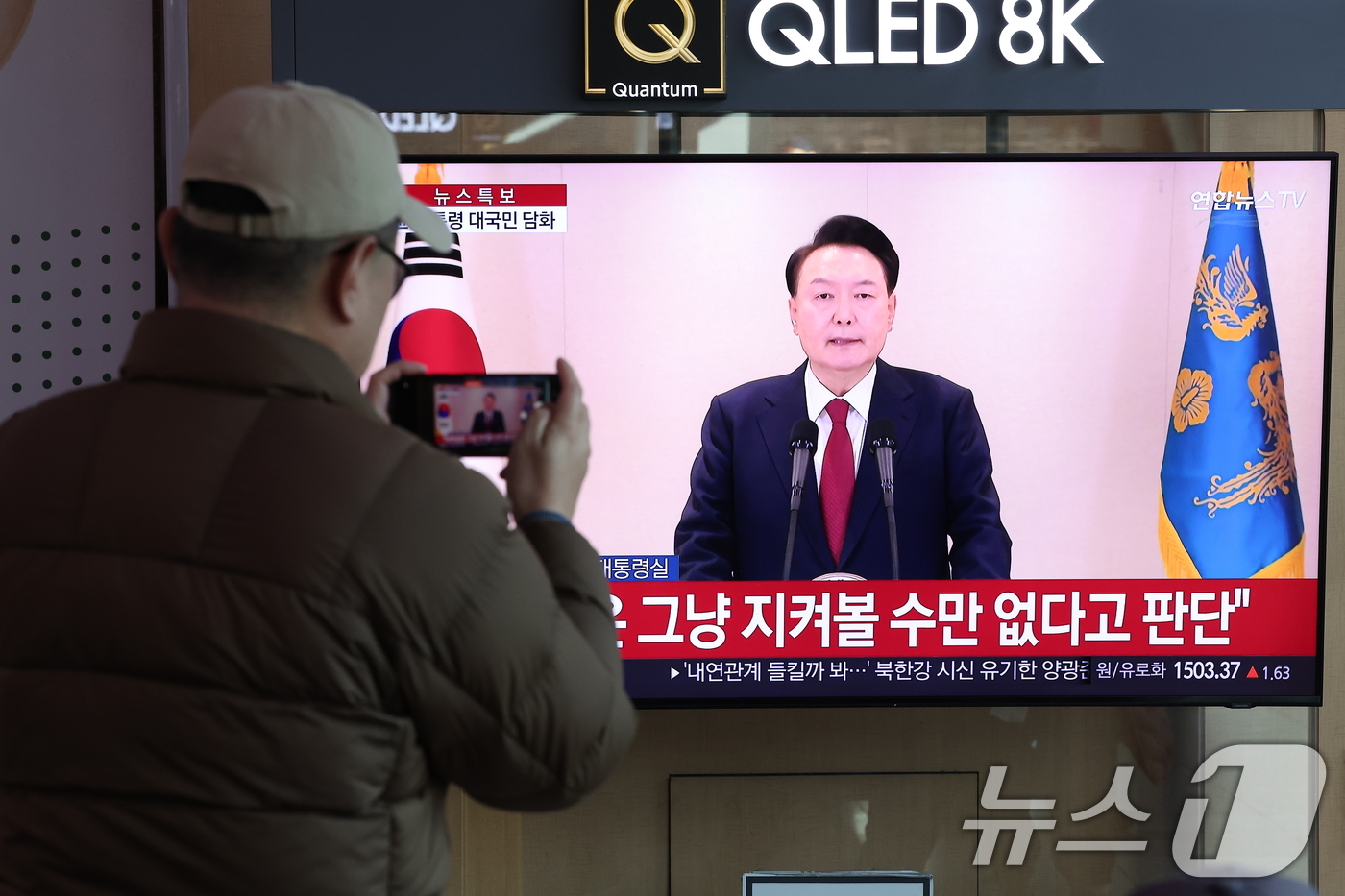 (서울=뉴스1) 김성진 기자 = 윤석열 대통령에 대한 국회의 탄핵소추안 발의일인 12일 서울 중구 서울역 대합실에서 시민들이 윤석열 대통령의 4번째 대국민 담화를 시청하고 있다. …