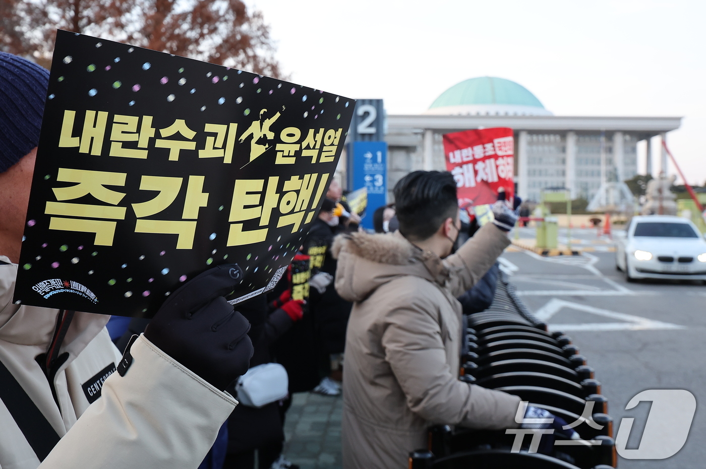 (서울=뉴스1) 김진환 기자 = 윤석열 대통령에 대한 국회의 2차 탄핵소추안 처리를 하루 앞둔 13일 오후 서울 영등포구 여의도 국회 앞에서 시민들이 윤대통령의 탄핵을 요구하는 손 …