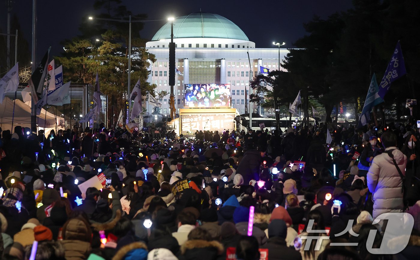 윤석열 대통령에 대한 국회의 2차 탄핵소추안 표결을 하루 앞둔 13일 오후 서울 영등포구 여의도 국회 앞에서 열린 &#39;윤석열 즉각 탄핵 구속 촉구 촛불문화제&#39;에서 참가자들이 응원봉과 손피켓을 들어 보이고 있다. 2024.12.13/뉴스1 ⓒ News1 김진환 기자