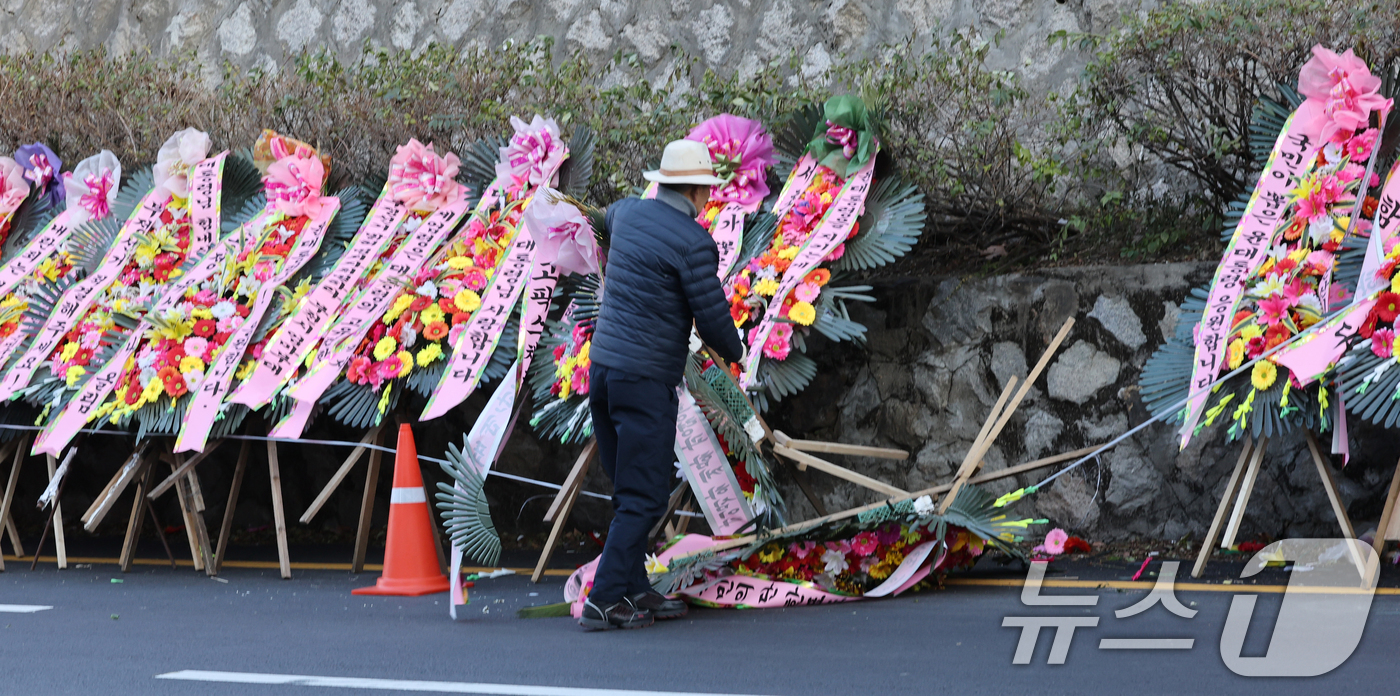 (서울=뉴스1) 송원영 기자 = 윤석열 대통령에 대한 국회 탄핵소추안이 가결된 14일 서울 용산 대통령실 인근에 윤 대통령 지지자가 바람에 쓰러진 화환을 정돈하고 있다. 2024. …