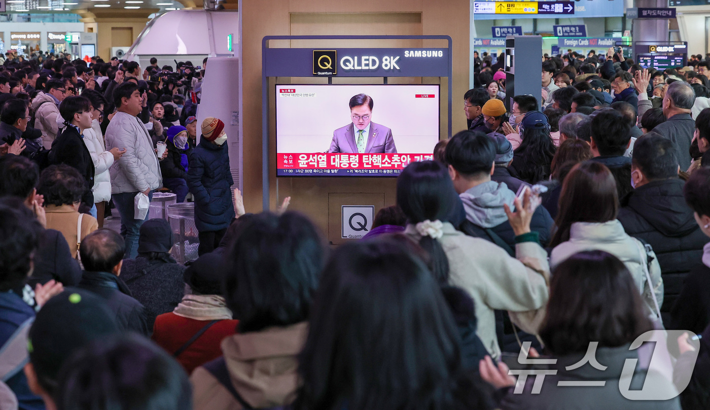 (서울=뉴스1) 김성진 기자 = 14일 서울 용산구 서울역 대합실에서 시민들이 윤석열 대통령에 대한 국회의 탄핵소추안이 가결되자 기뻐하고 있다.이날 국회 본회의에선 재적의원 300 …