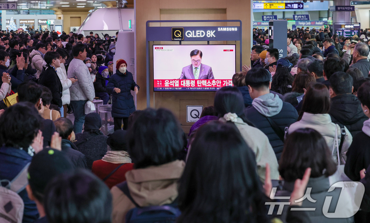 (서울=뉴스1) 김성진 기자 = 14일 서울 용산구 서울역 대합실에서 시민들이 윤석열 대통령에 대한 국회의 탄핵소추안이 가결되자 기뻐하고 있다.이날 국회 본회의에선 재적의원 300 …