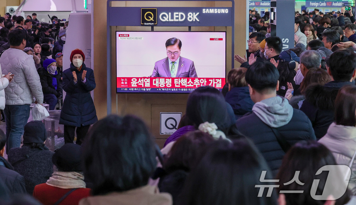 (서울=뉴스1) 김성진 기자 = 14일 서울 용산구 서울역 대합실에서 시민들이 윤석열 대통령에 대한 국회의 탄핵소추안이 가결되자 기뻐하고 있다.이날 국회 본회의에선 재적의원 300 …