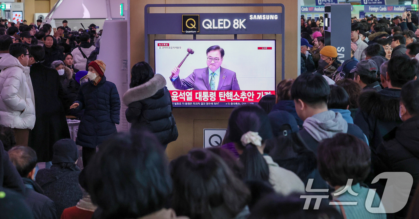 (서울=뉴스1) 김성진 기자 = 14일 서울 용산구 서울역 대합실에서 시민들이 윤석열 대통령에 대한 국회의 탄핵소추안이 가결되자 기뻐하고 있다.이날 국회 본회의에선 재적의원 300 …