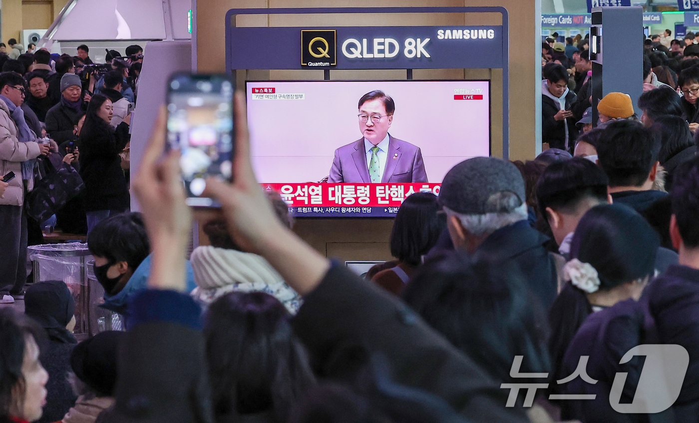 (서울=뉴스1) 김성진 기자 = 14일 서울 용산구 서울역 대합실에서 시민들이 윤석열 대통령에 대한 국회의 탄핵소추안이 가결되자 기뻐하고 있다.이날 국회 본회의에선 재적의원 300 …