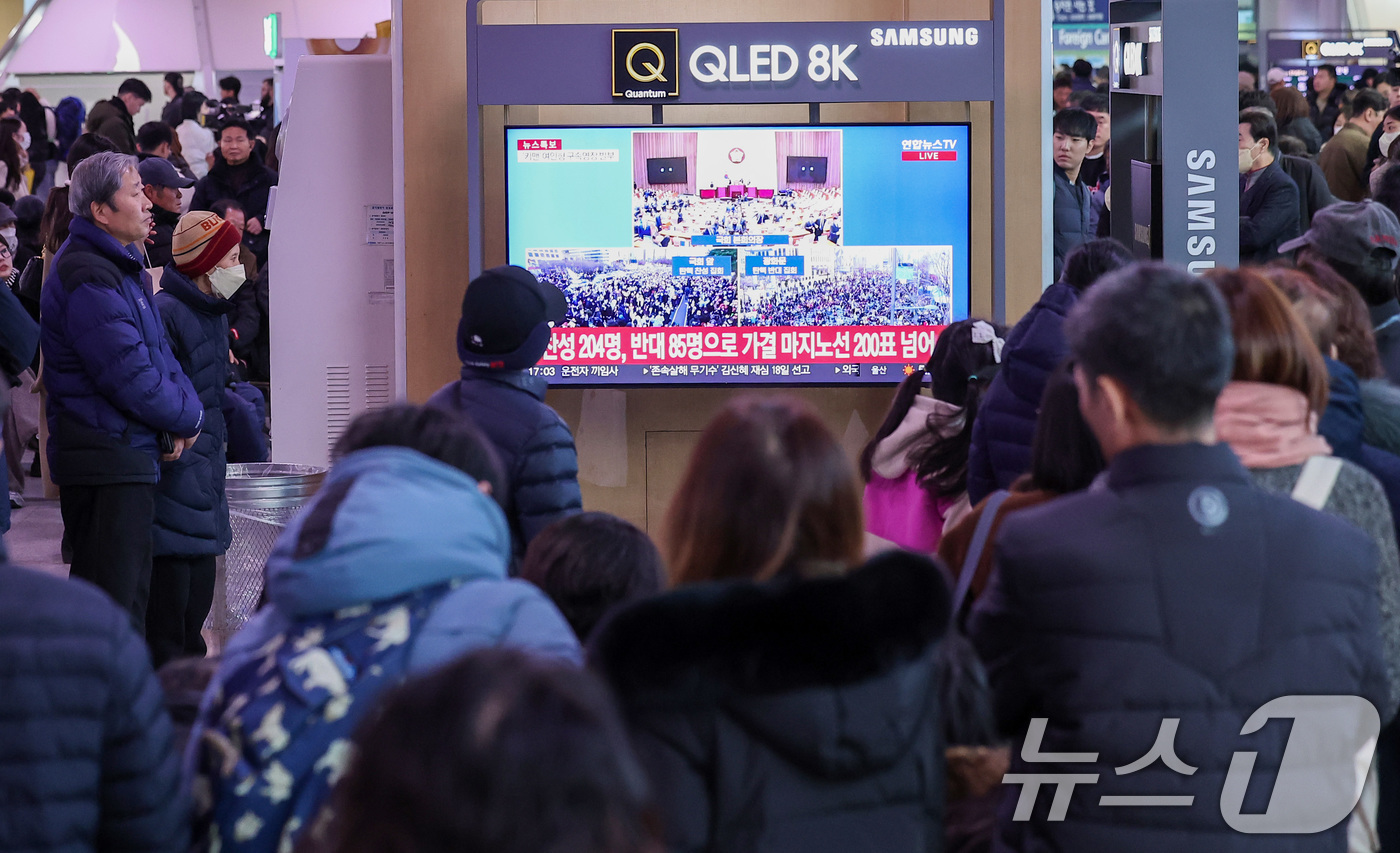 (서울=뉴스1) 김성진 기자 = 14일 서울 용산구 서울역 대합실에서 시민들이 윤석열 대통령에 대한 국회의 탄핵소추안이 가결되자 기뻐하고 있다.이날 국회 본회의에선 재적의원 300 …