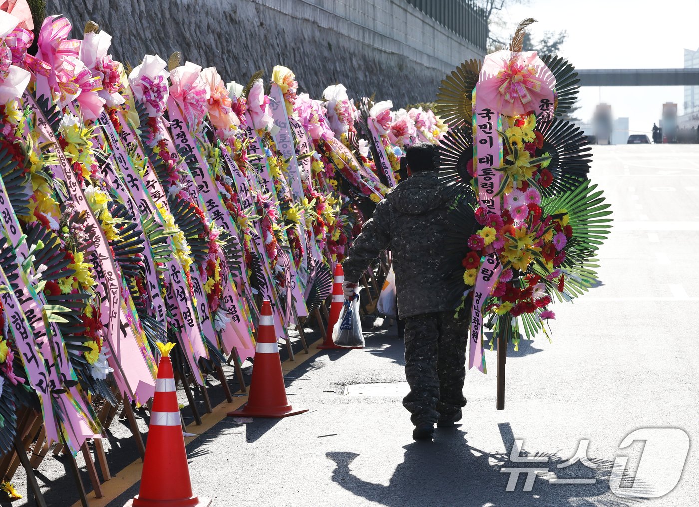 본문 이미지 - 윤석열 대통령에 대한 국회 탄핵소추안이 가결된 가운데 15일 서울 용산 대통령실 인근에서 윤 대통령 지지자들이 화환을 정돈하고 있다. 2024.12.15/뉴스1 ⓒ News1 송원영 기자