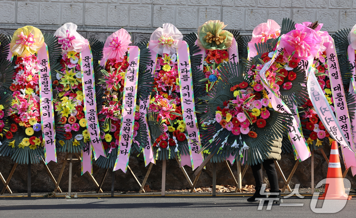 (서울=뉴스1) 송원영 기자 = 윤석열 대통령에 대한 국회 탄핵소추안이 가결된 가운데 15일 서울 용산 대통령실 인근에서 윤 대통령 지지자들이 화환을 정돈하고 있다. 2024.12 …