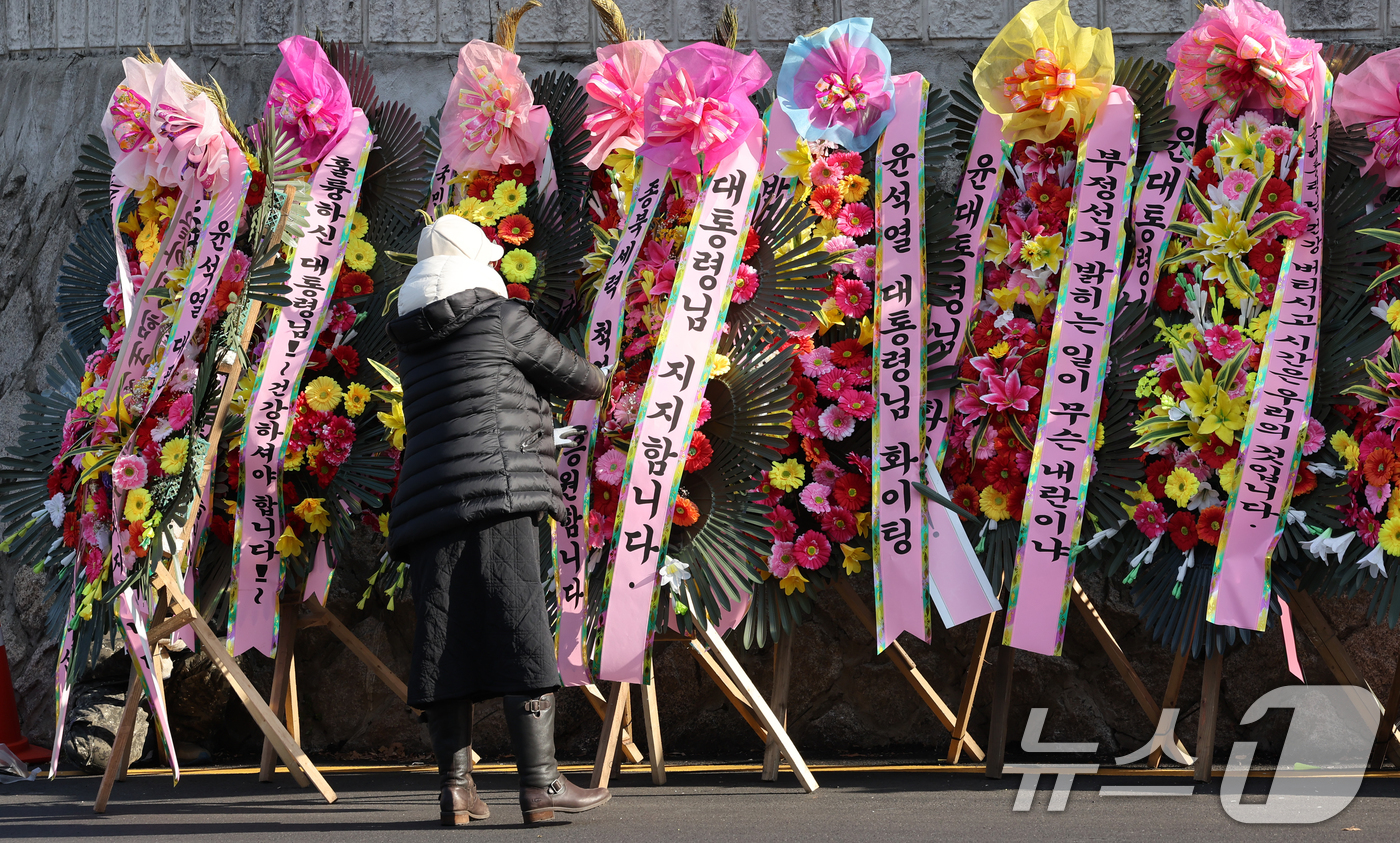 (서울=뉴스1) 송원영 기자 = 윤석열 대통령에 대한 국회 탄핵소추안이 가결된 가운데 15일 서울 용산 대통령실 인근에서 윤 대통령 지지자들이 화환을 정돈하고 있다. 2024.12 …