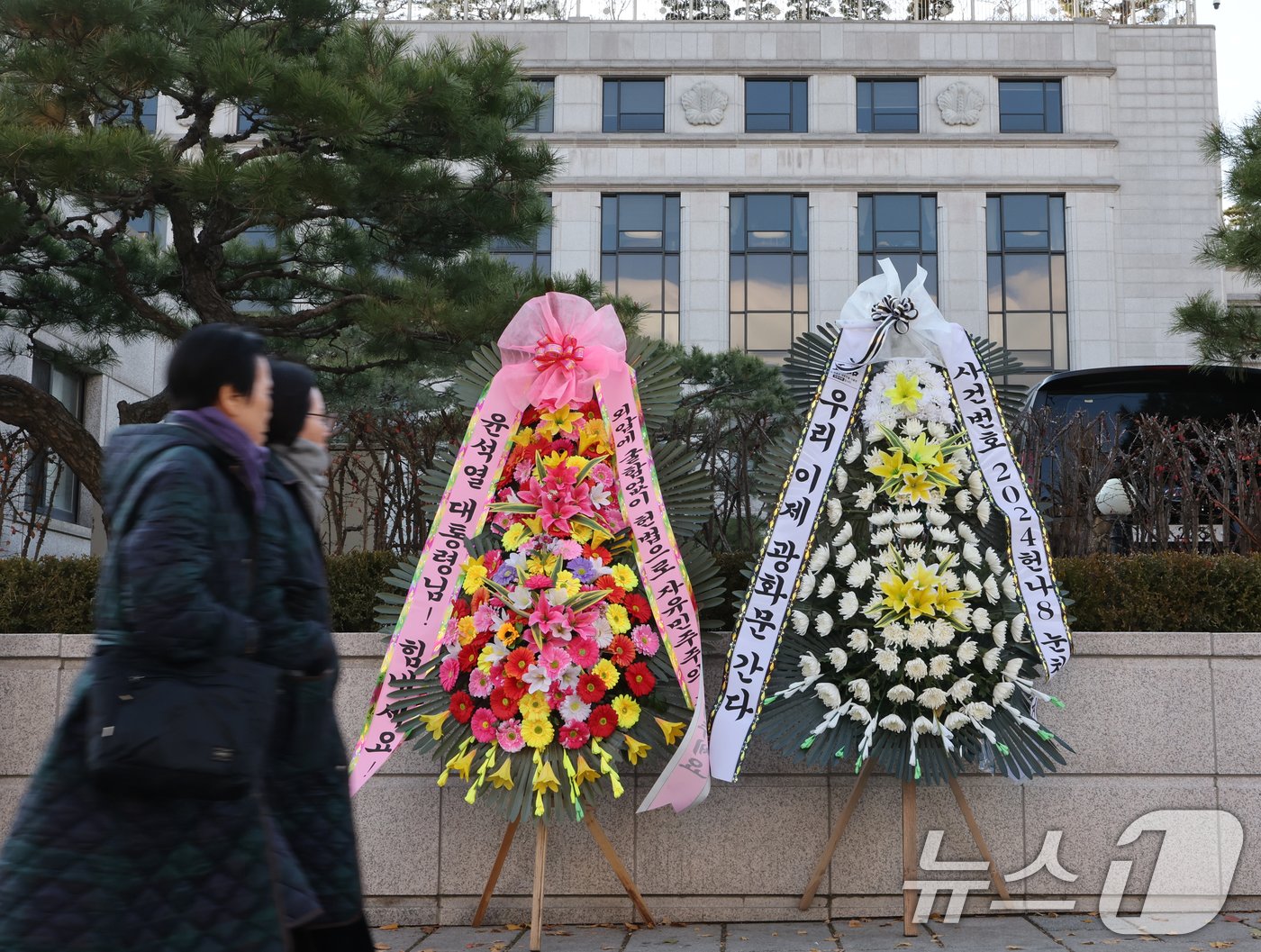 윤석열 대통령 탄핵소추안이 국회에서 가결되면서 공이 헌법재판소로 넘어왔다. 탄핵 사건이 접수되면 헌법재판소는 180일 내에 대통령 파면 여부를 결정해야 한다. 15일 서울 종로구 헌법재판소 앞에 윤석열 대통령의 응원 화환과 탄핵 촉구 화한이 나란히 놓여 있다. 2024.12.15/뉴스1 ⓒ News1 송원영 기자