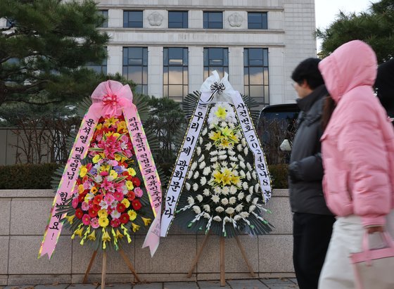 윤석열 대통령 탄핵소추안이 국회에서 가결되면서 공이 헌법재판소로 넘어왔다. 탄핵 사건이 접수되면 헌법재판소는 180일 내에 대통령 파면 여부를 결정해야 한다. 15일 서울 종로구 헌법재판소 앞에 윤석열 대통령의 응원 화환과 탄핵 촉구 화한이 나란히 놓여 있다. 2024.12.15/뉴스1 ⓒ News1 송원영 기자